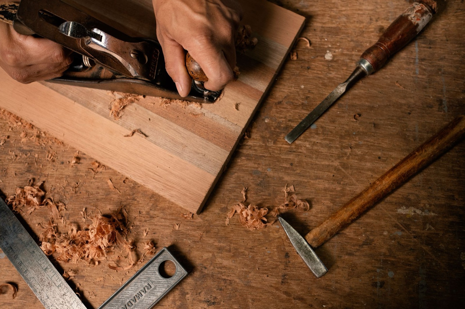 Craftsman's hands measuring and marking a piece of wood