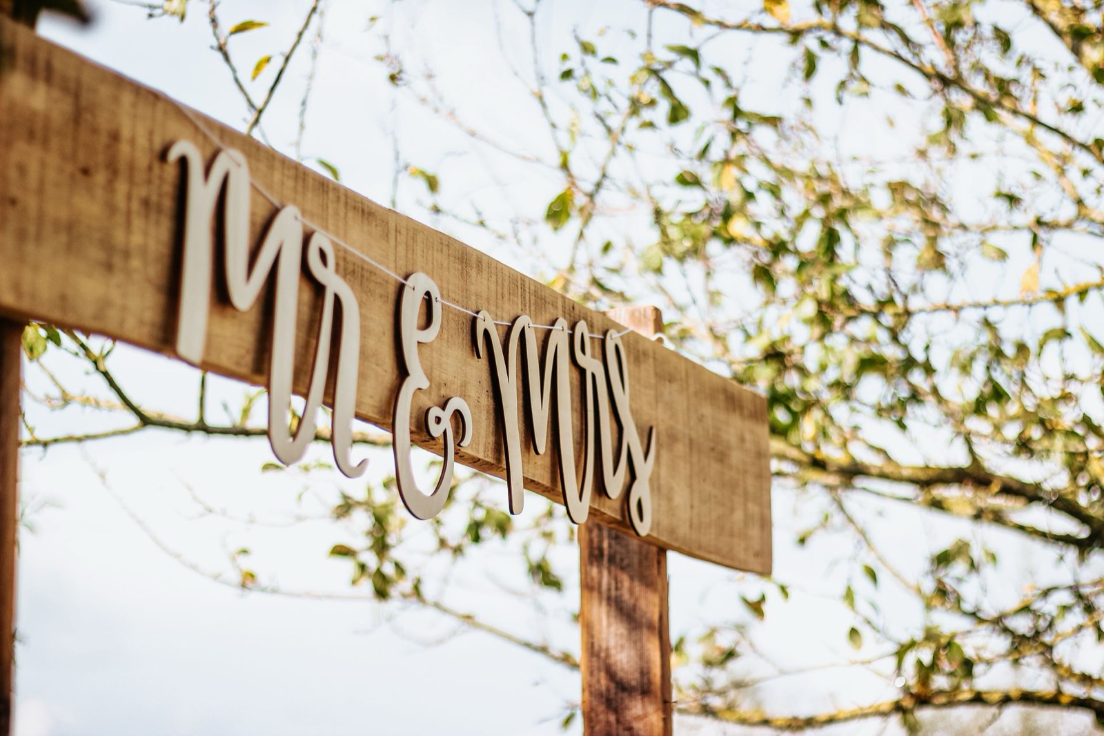 Rustic wood wedding sign hanging outdoors
