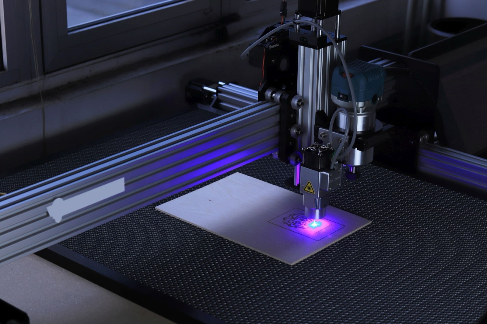 A laser engraver etching a design into a sheet of birch plywood
